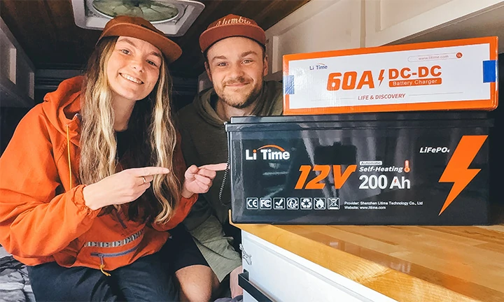 a couple inside their camper van pointing to their new LiTime 12V 200Ah self-heating battery and 60A DC-DC battery charger