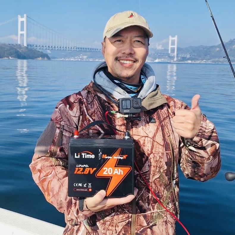 A fisherman on his boat holds a LiTime 12V 20Ah starting battery and gives a thumbs-up