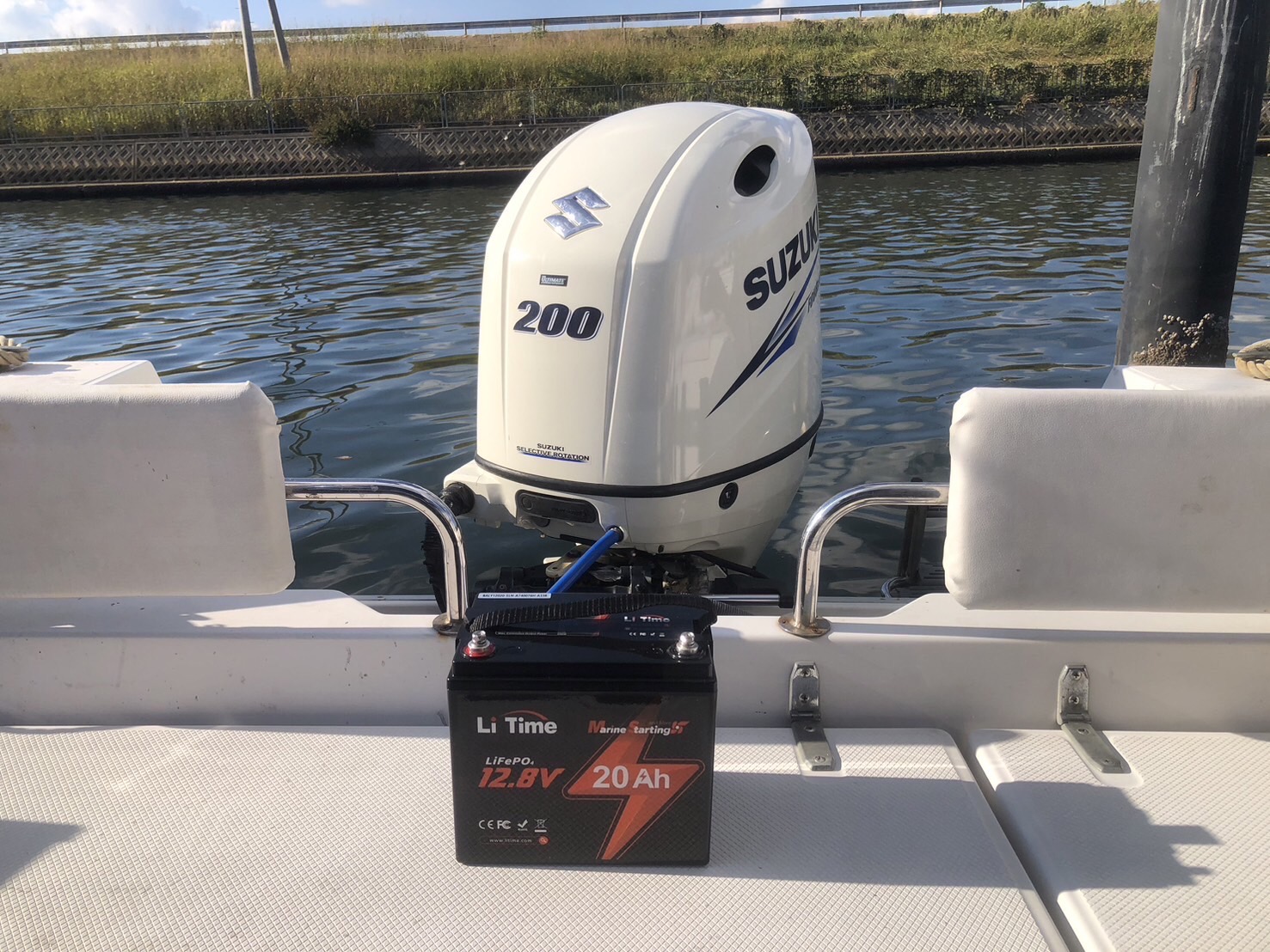 a LiTime 12V 20Ah marine starting battery installed on a boat, wired to a 200HP Suzuki outboard motor