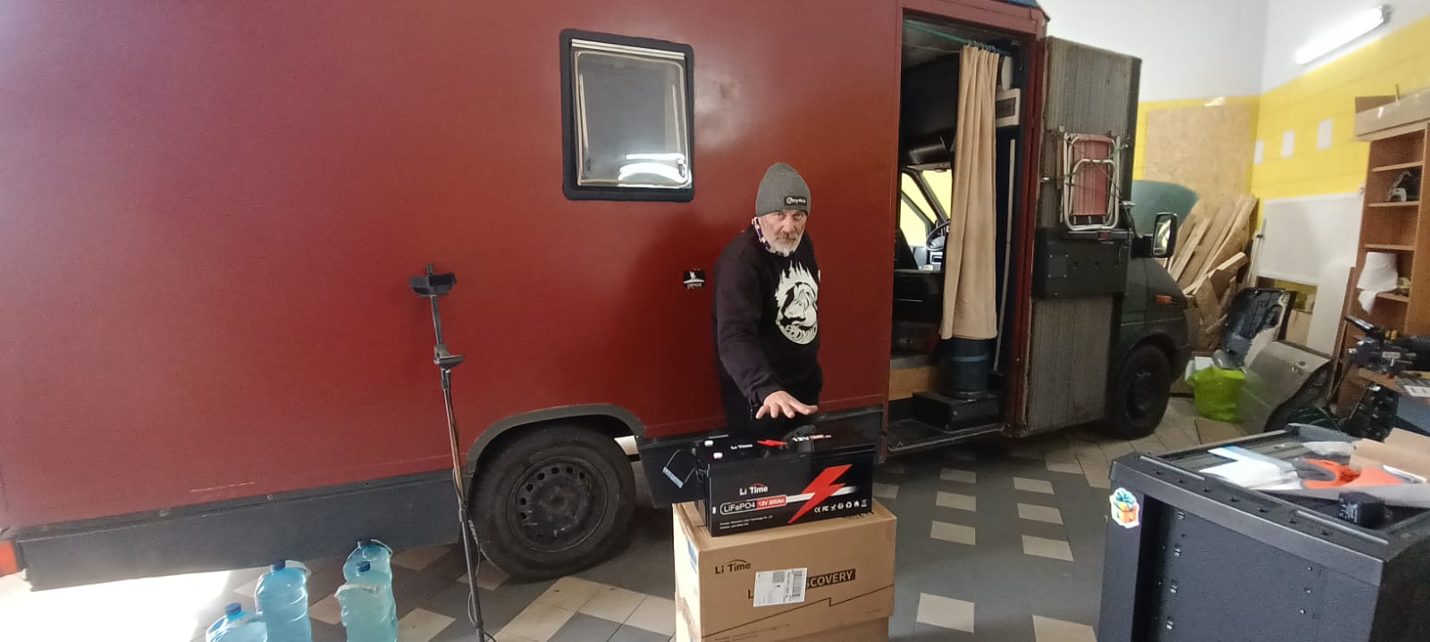 A customer installing a LiTime 12V 200Ah lithium battery into their red camper van